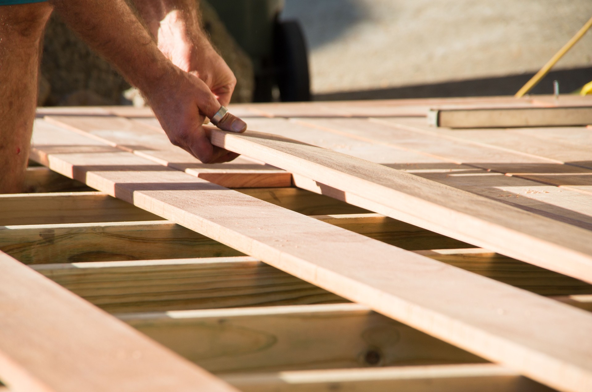 Man placing a plank of wood in a deck home renovation